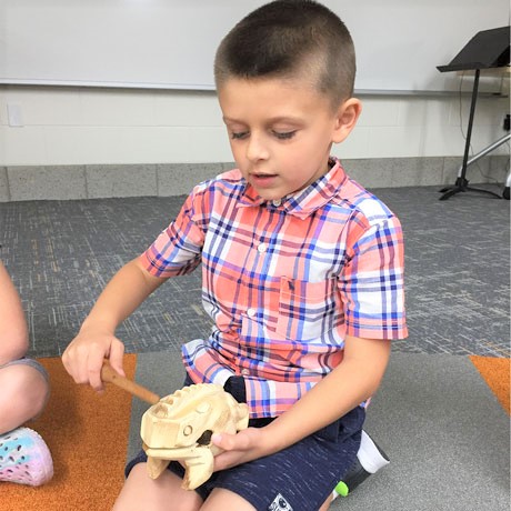 Preschool boy wearing plaid shirt practicing keeping a beat